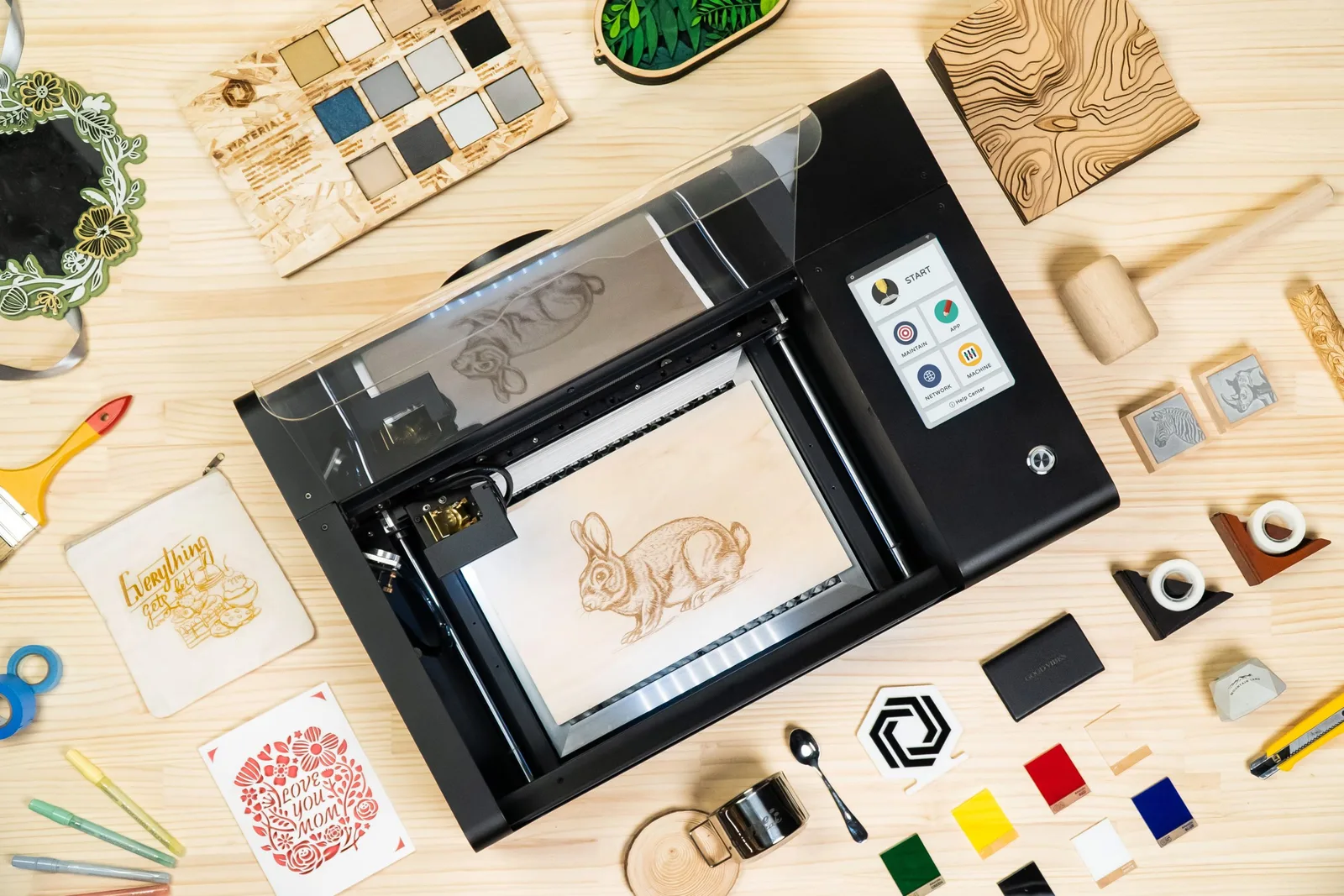 beamo laser cutter surrounded by engraved and cut projects