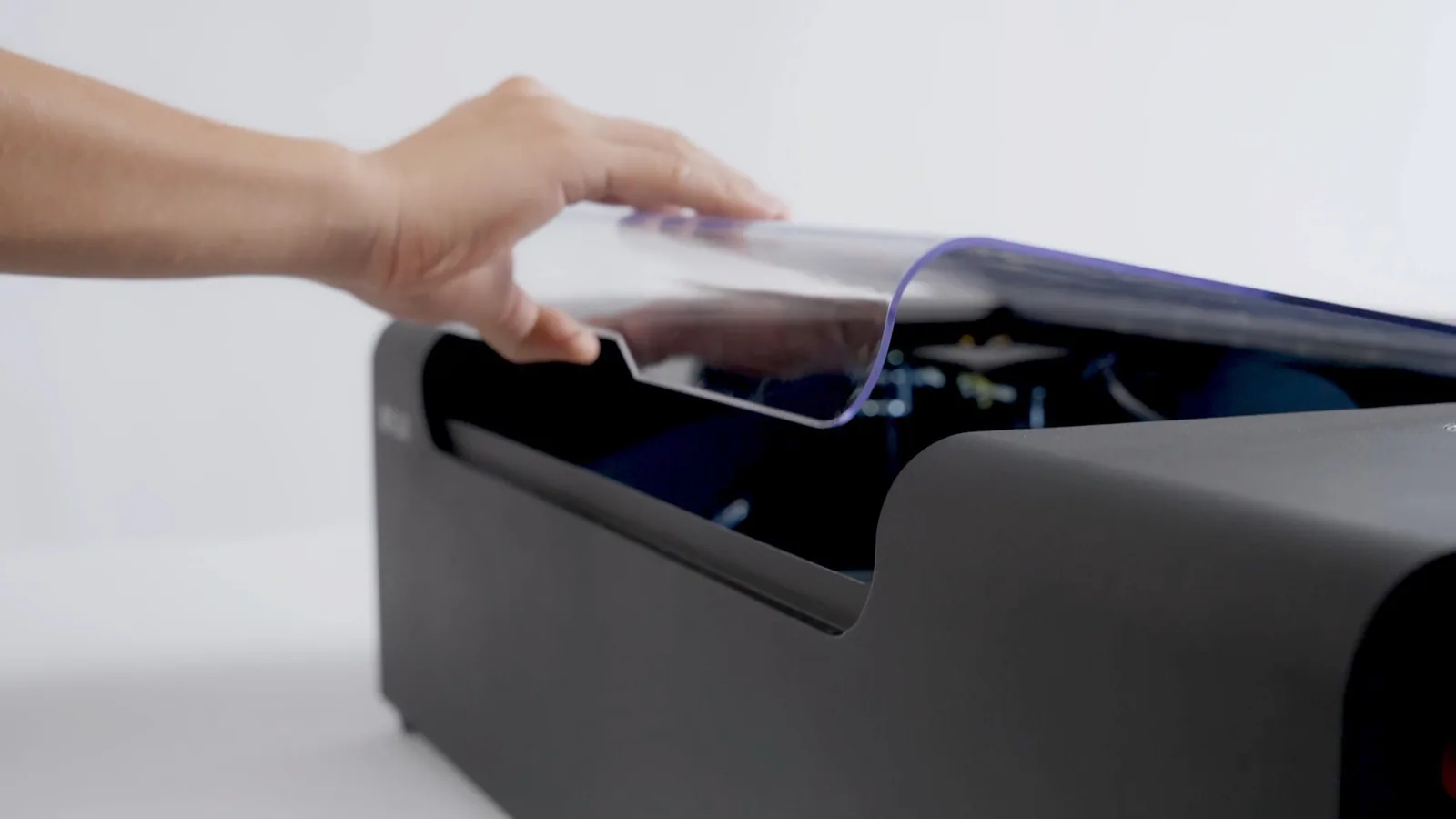 A hand opening the enclosed beamo II laser cutter lid