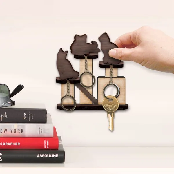 A cat-shaped wooden key holder beside a stack of books