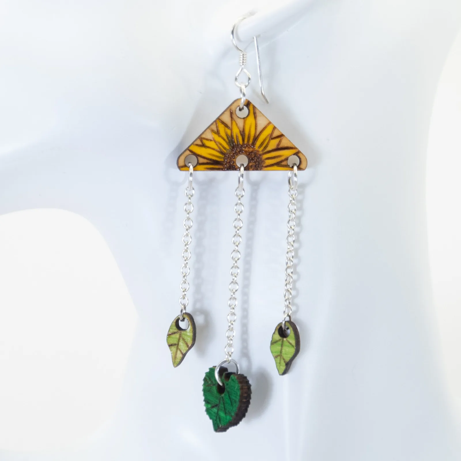 A layered wooden sunflower earring with hanging leaves