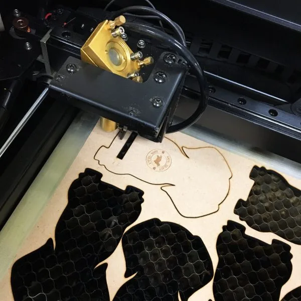 Pet-shaped wooden pieces being cut in a laser cutter