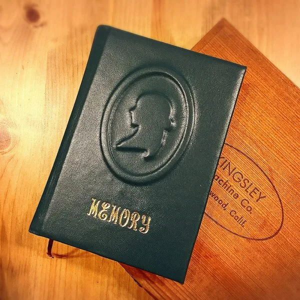 A finished green LEPAU leather notebook embossed with a cameo and the word Memory