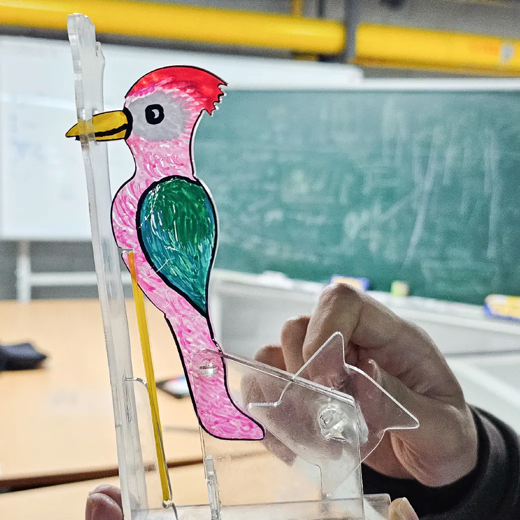 A student operating a colorful bird automata built from waste acrylic